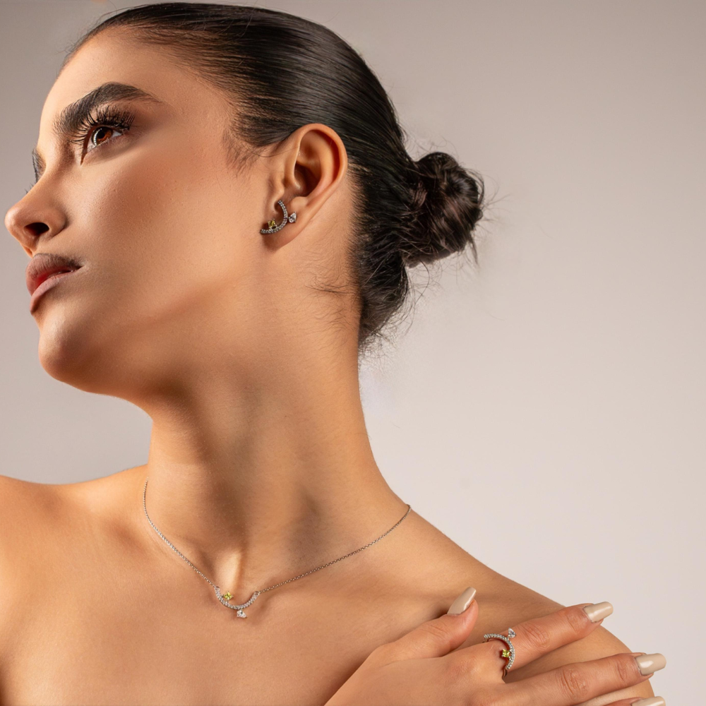 Woman wearing a necklace and earrings against a neutral background