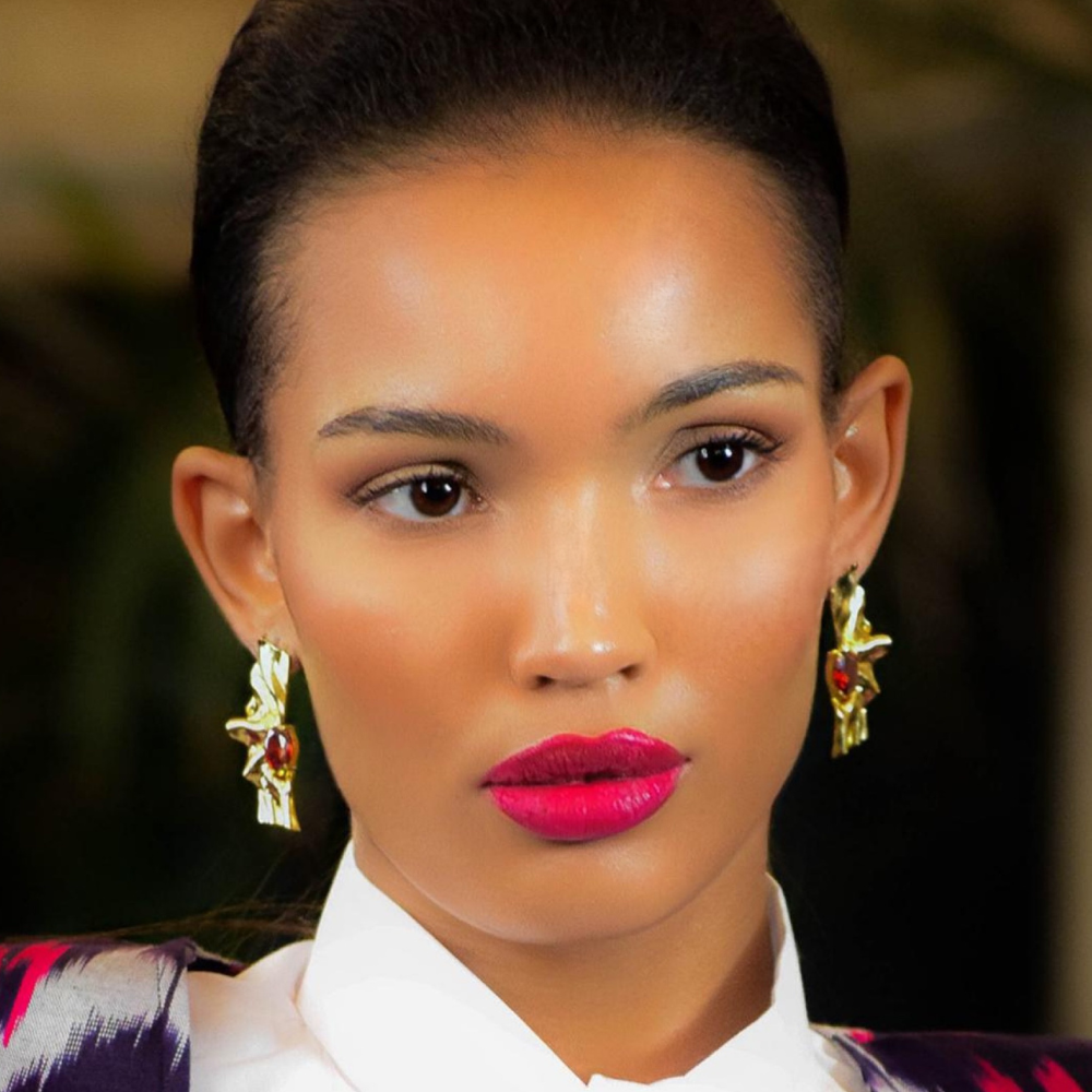 Woman wearing Victoria gold-plated sterling silver earrings with deep red cubic zirconia garnet stones
