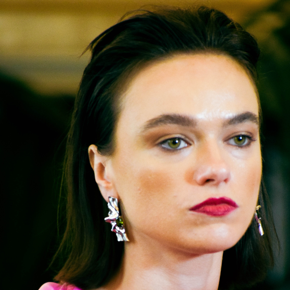 Woman wearing Victoria sterling silver earrings with olive green cubic zirconia stones