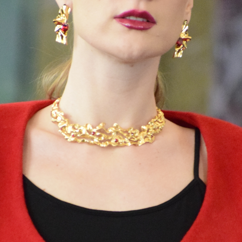 woman wearing a gold-plated choker necklace with deep red cubic zirconia garnet gemstones.