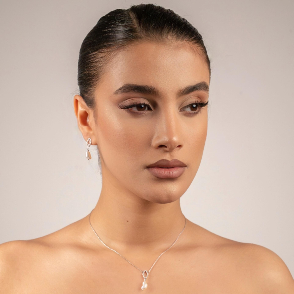 Woman wearing a necklace with a clear pendant against a neutral background