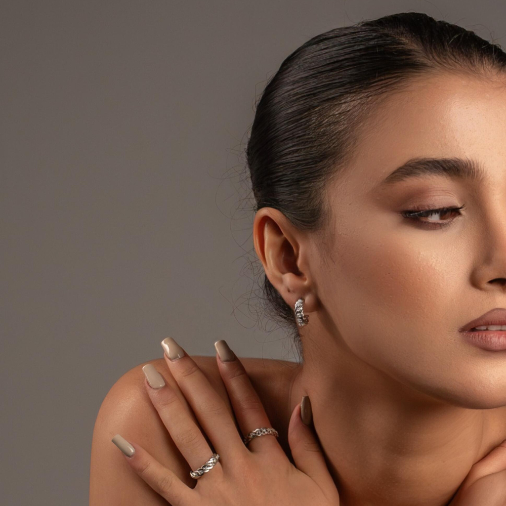 Woman wearing earrings and rings with a neutral background