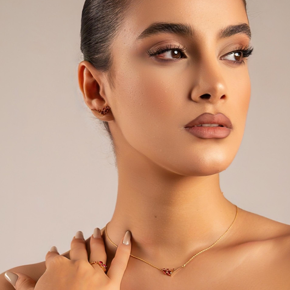 Close-up of a woman wearing a delicate necklace against a neutral background