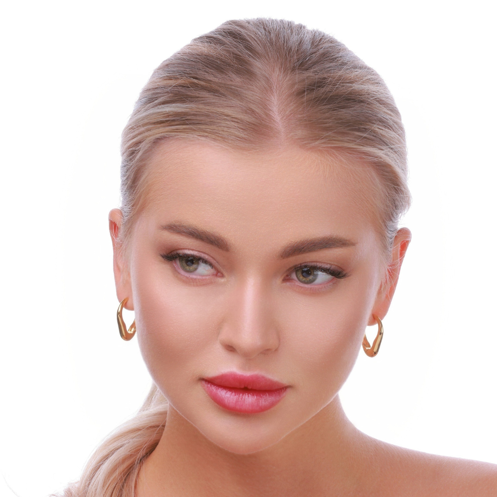 Woman wearing gold-plated heart-shaped hoop earrings in 925 sterling silver