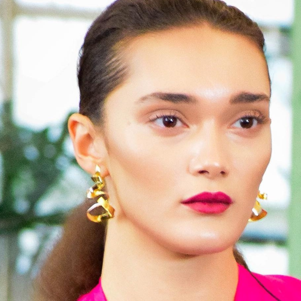 Woman wearing Jade gold-plated spiral earrings with modern elegant design