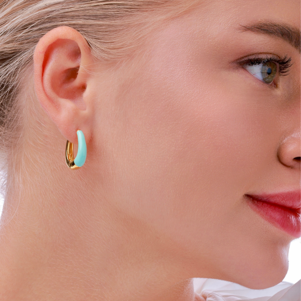 Woman wearing Luna gold-plated chunky hoop earrings with baby blue enamel