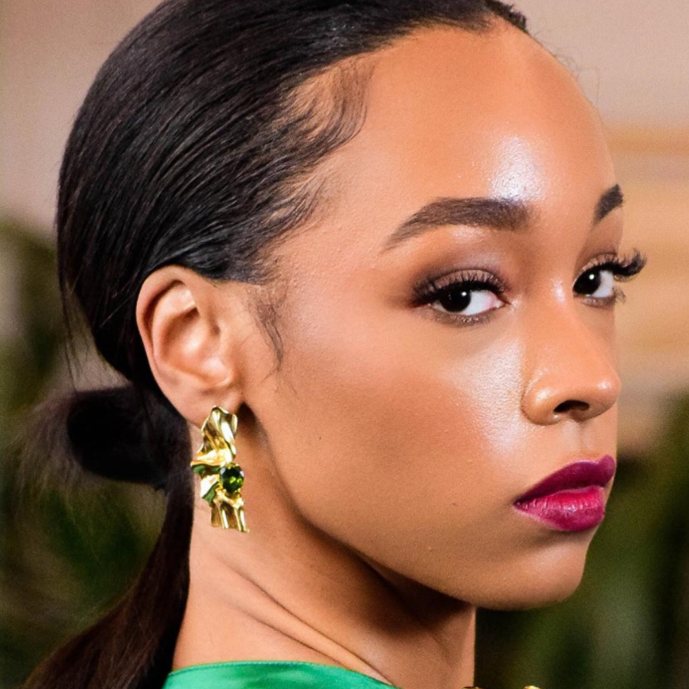 Woman wearing Victoria gold-plated sterling silver earrings with olive green cubic zirconia stones