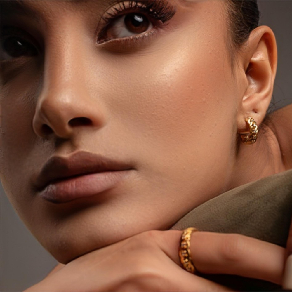 Close-up of a woman wearing gold hoop earrings and a ring