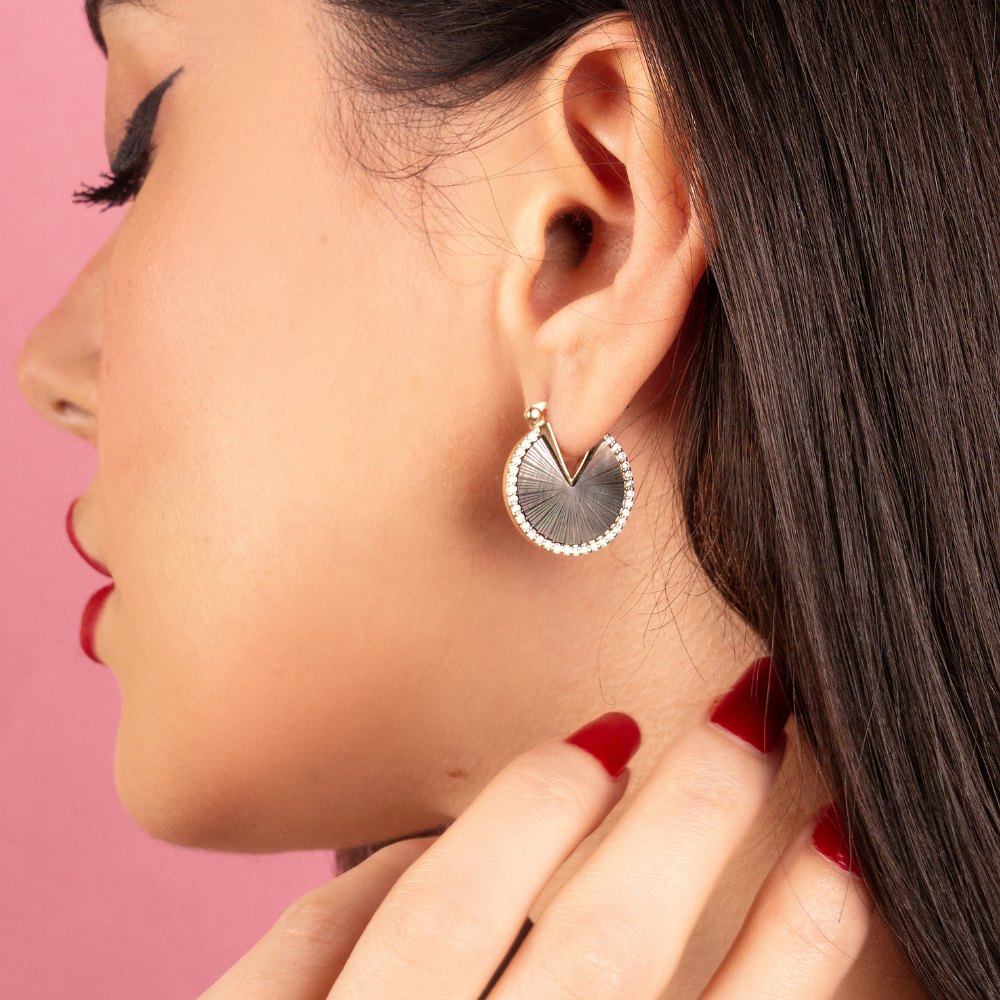 Woman wearing Audrey gold-plated earrings with white cubic zirconia and black mother-of-pearl stone
